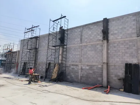 Muro perimetral con andamios durante la construcción, nave industrial en curso de CODISA